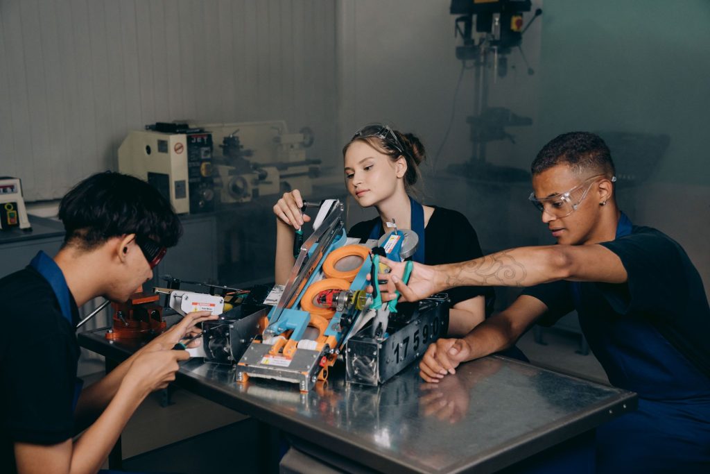 Three students assembling a robotics project at a workshop table
