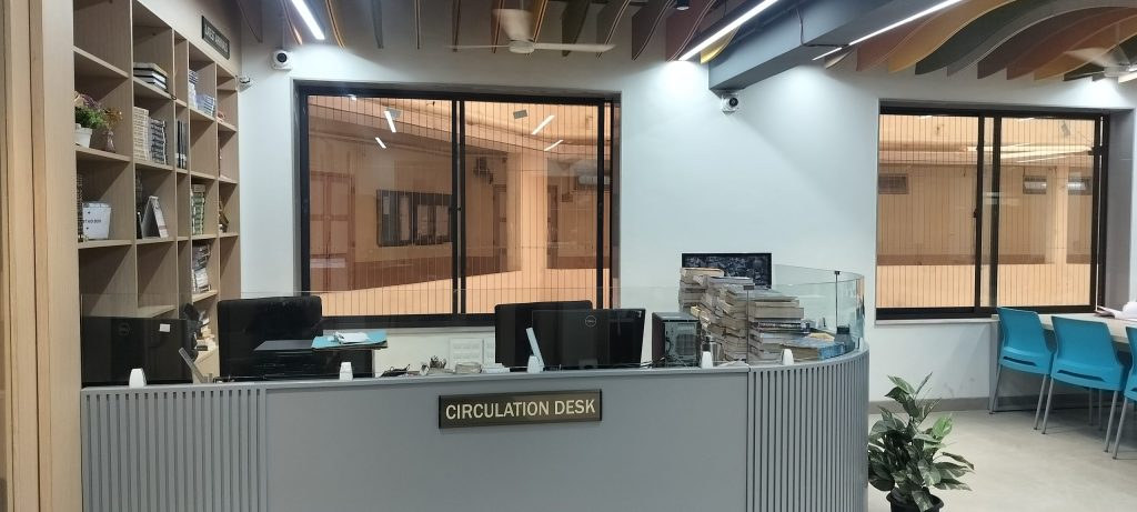 The library circulation desk with bookshelves behind it