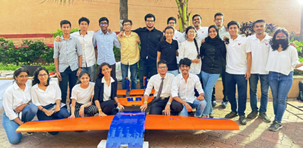 Students posing with their orange and blue aircraft